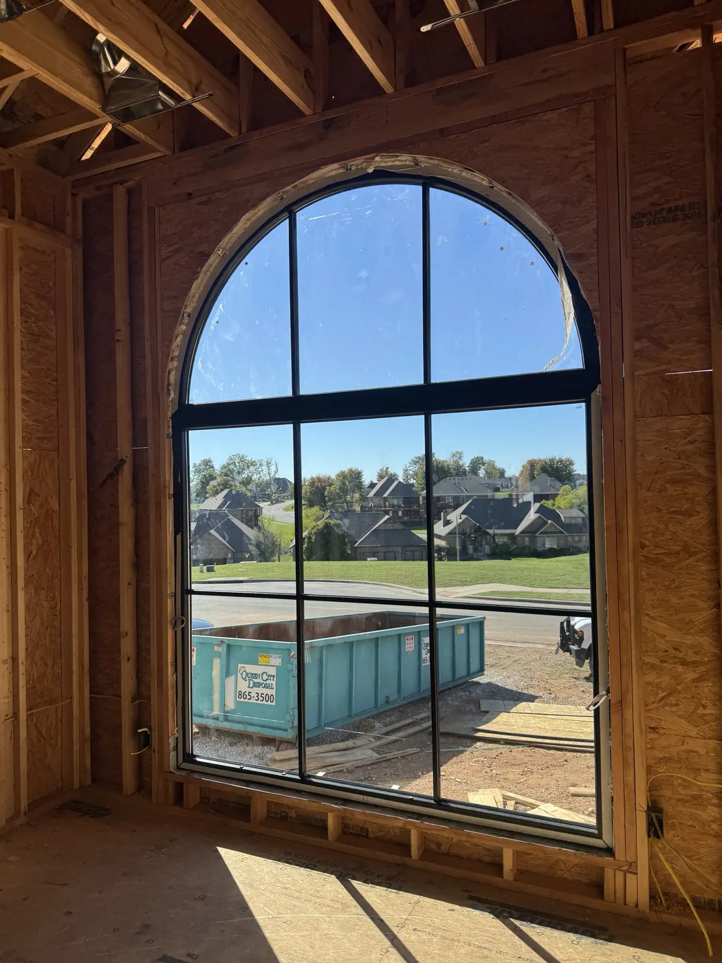 Arched window with black frame and divided panes, set in a framed wall